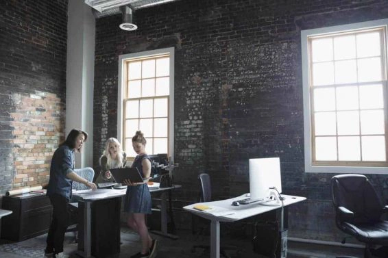 Creative business people with laptop meeting in loft office