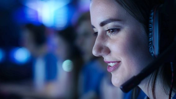 Beautiful professional gamer girl and her team participate in esport cyber games tournament. she has her headphones and talks into microphone.