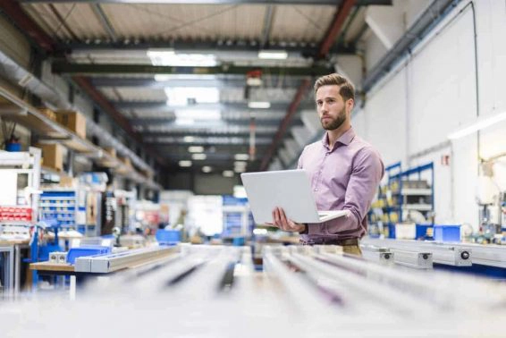 Young businessman using laptop in production hall