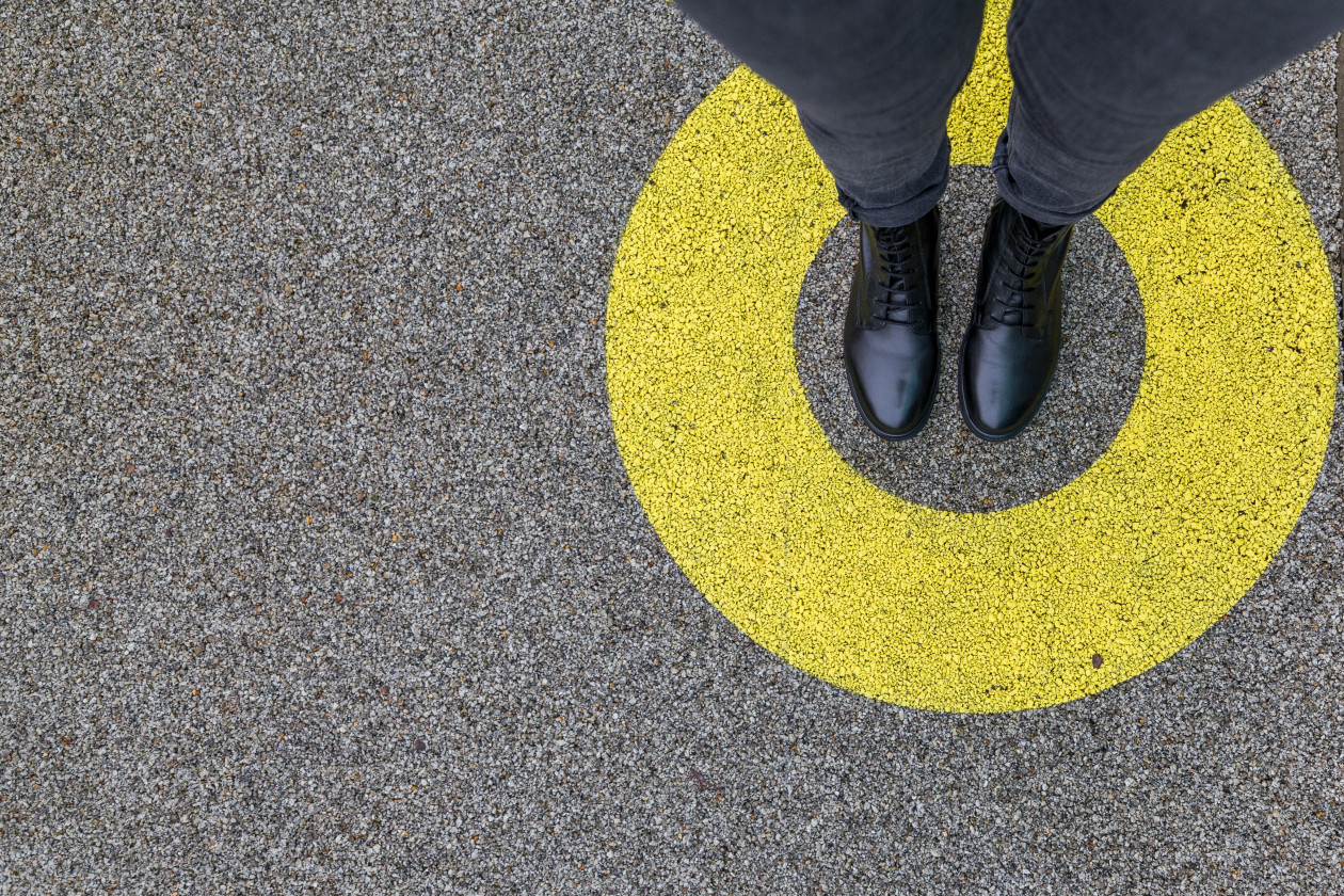 Black shoes standing in yellow circle on the asphalt concrete floor. comfort zone or frame concept. feet standing inside comfort zone circle. place for text, banner