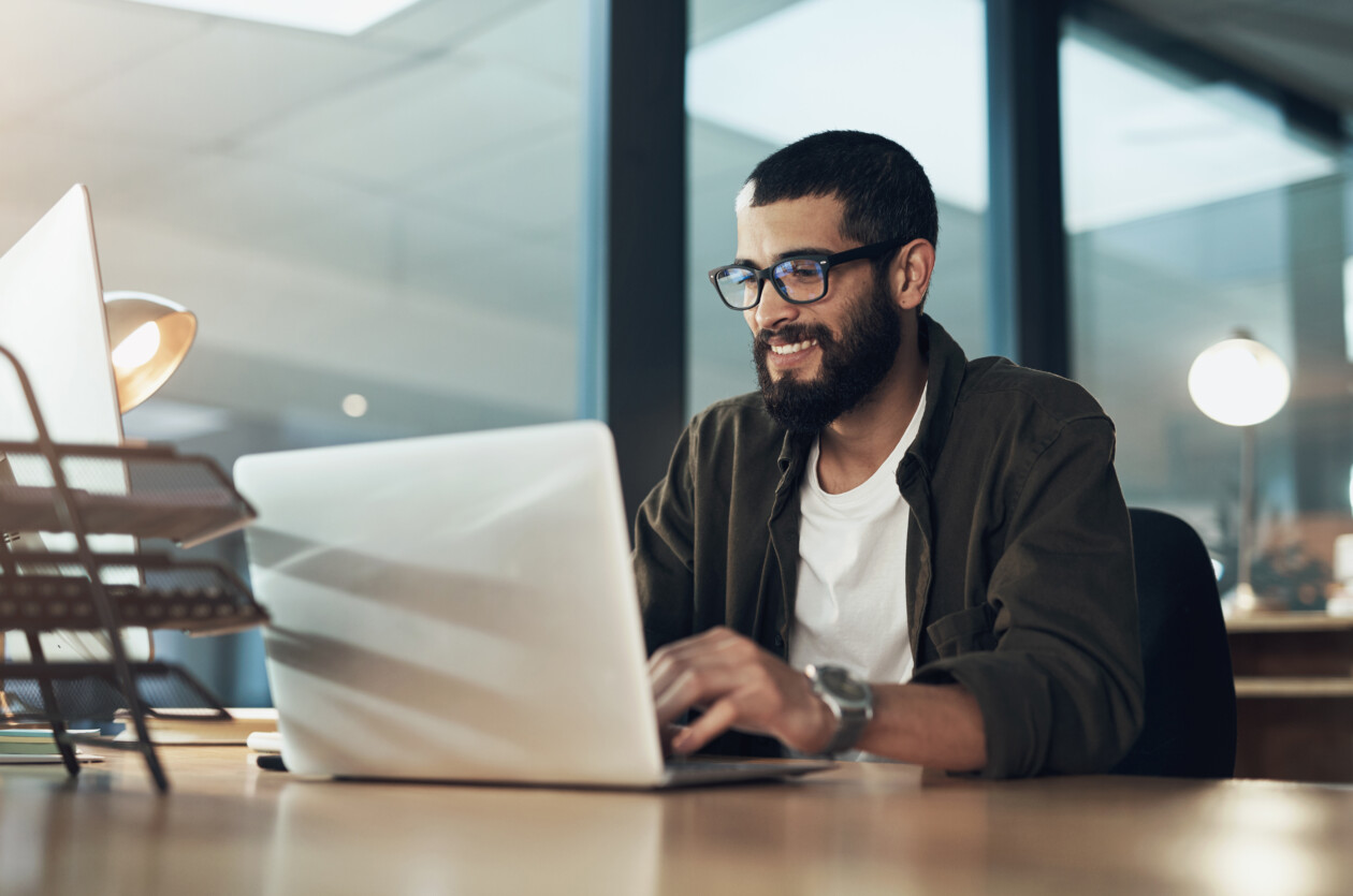 Smile, work and a businessman with a laptop for an email, communication or online coding. happy, programming and a male programmer typing on a computer for web or software development in an office