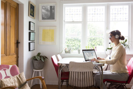 A woman works from her home at the table in her kitchen