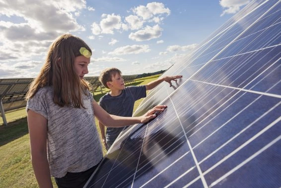 Boy and girl standing next to solar panels