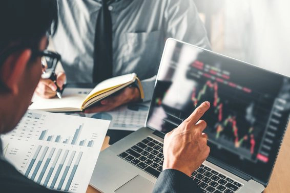 Midsection businessmen analyzing charts on laptop in office