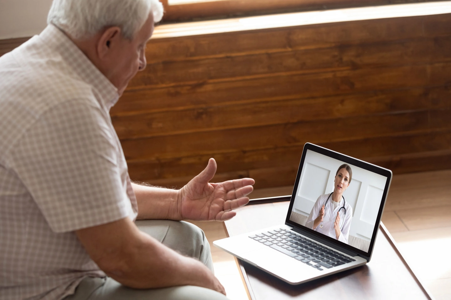 Focused older 80s patient consulting with doctor via video call.