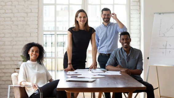 Four multiracial businesspeople during group meeting posing looking at camera