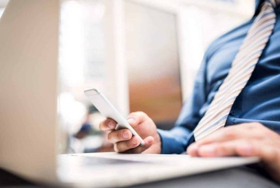 An unrecognizable young businessman with laptop and smartphone, working.