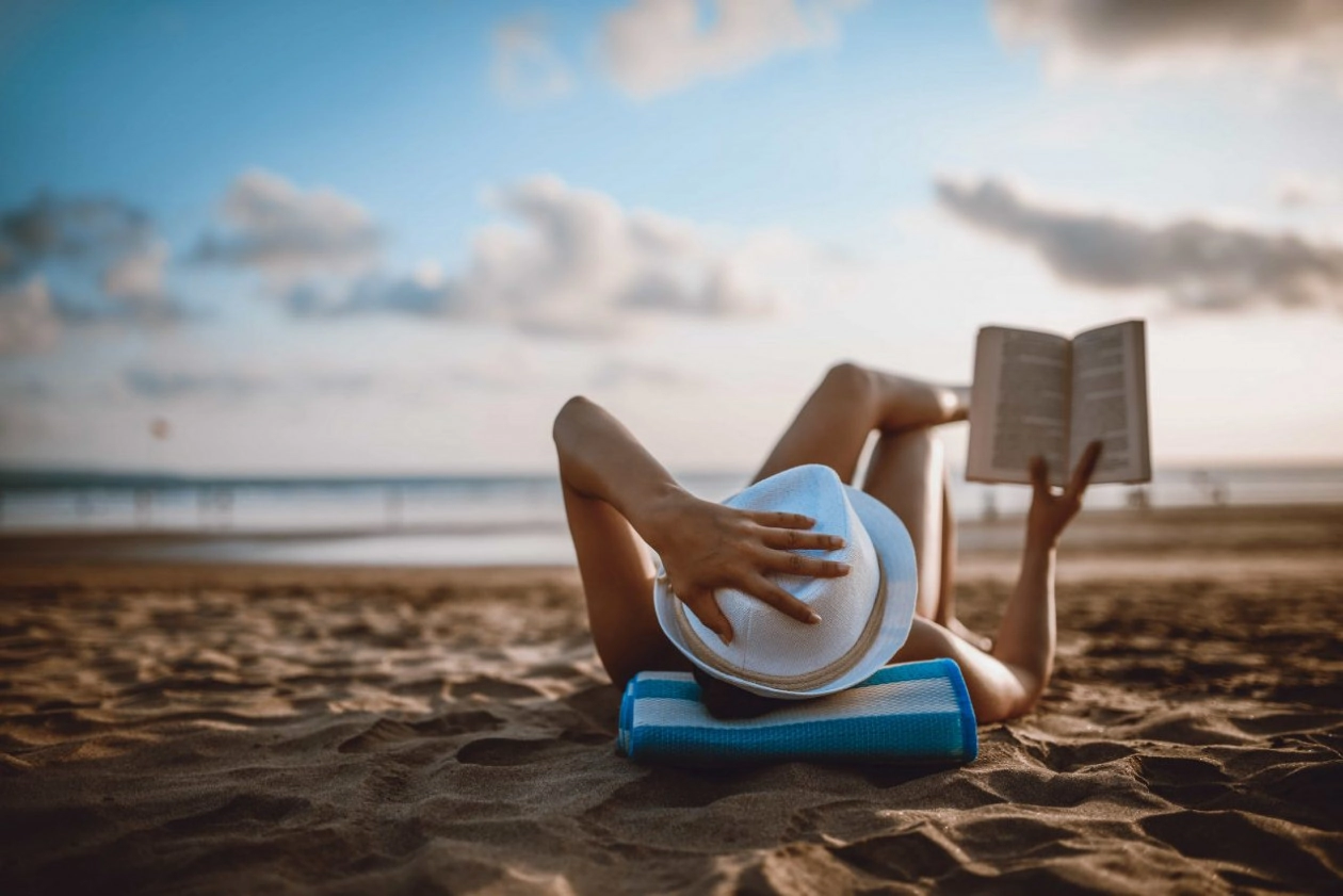 Female reading and enjoying sunset on beach by the ocean