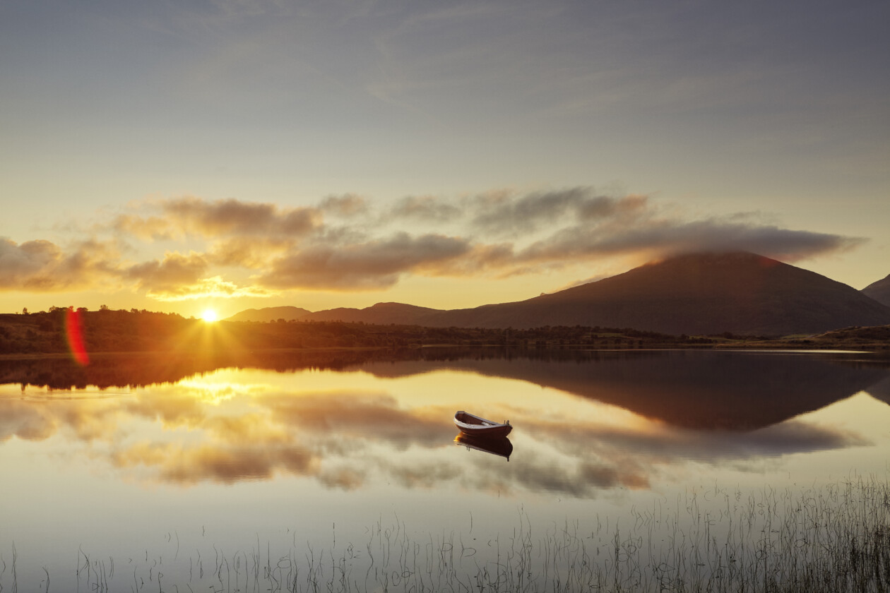 Boat reflected on lake at sunset